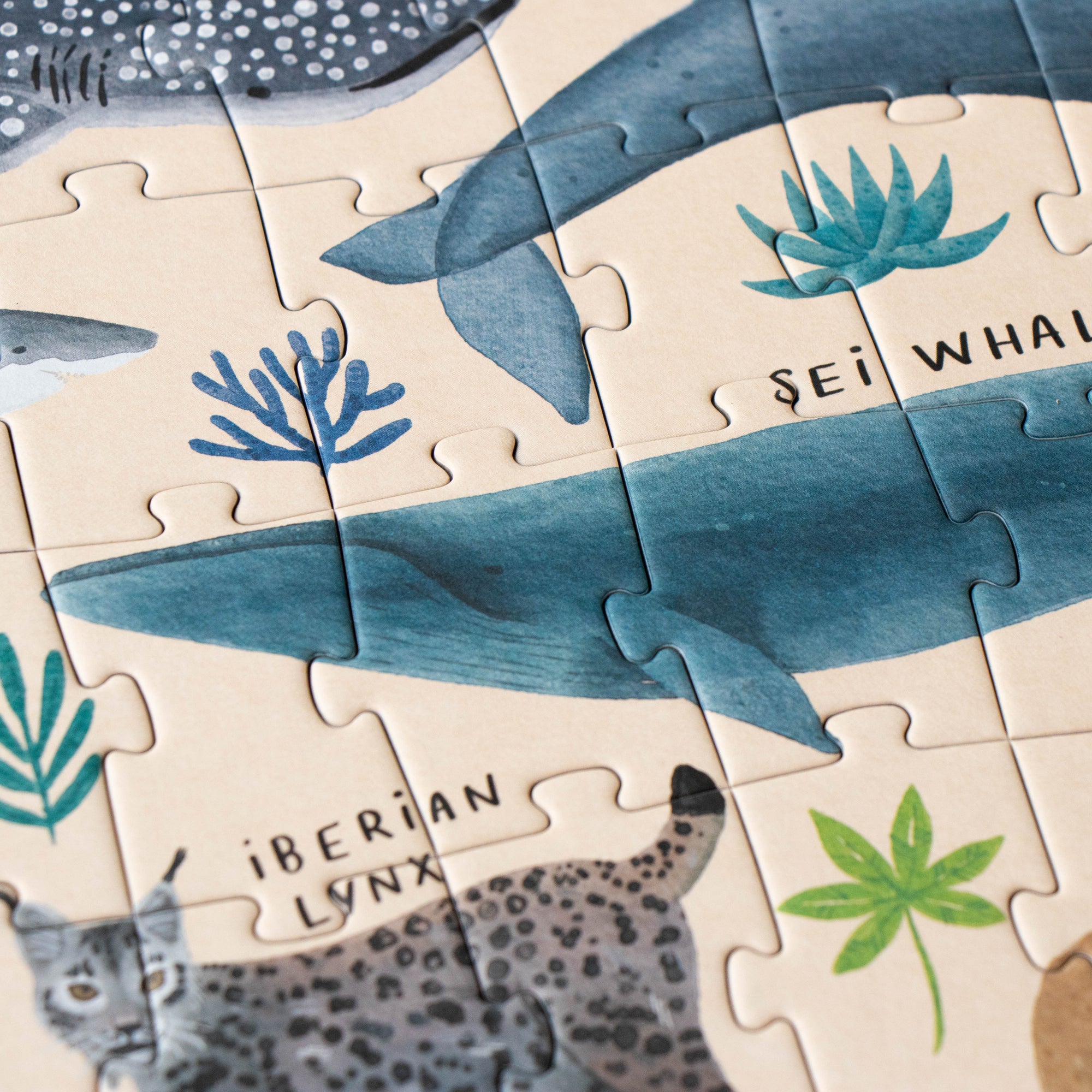 Jigsaw puzzle with whale and lynx illustrations on a beige background
