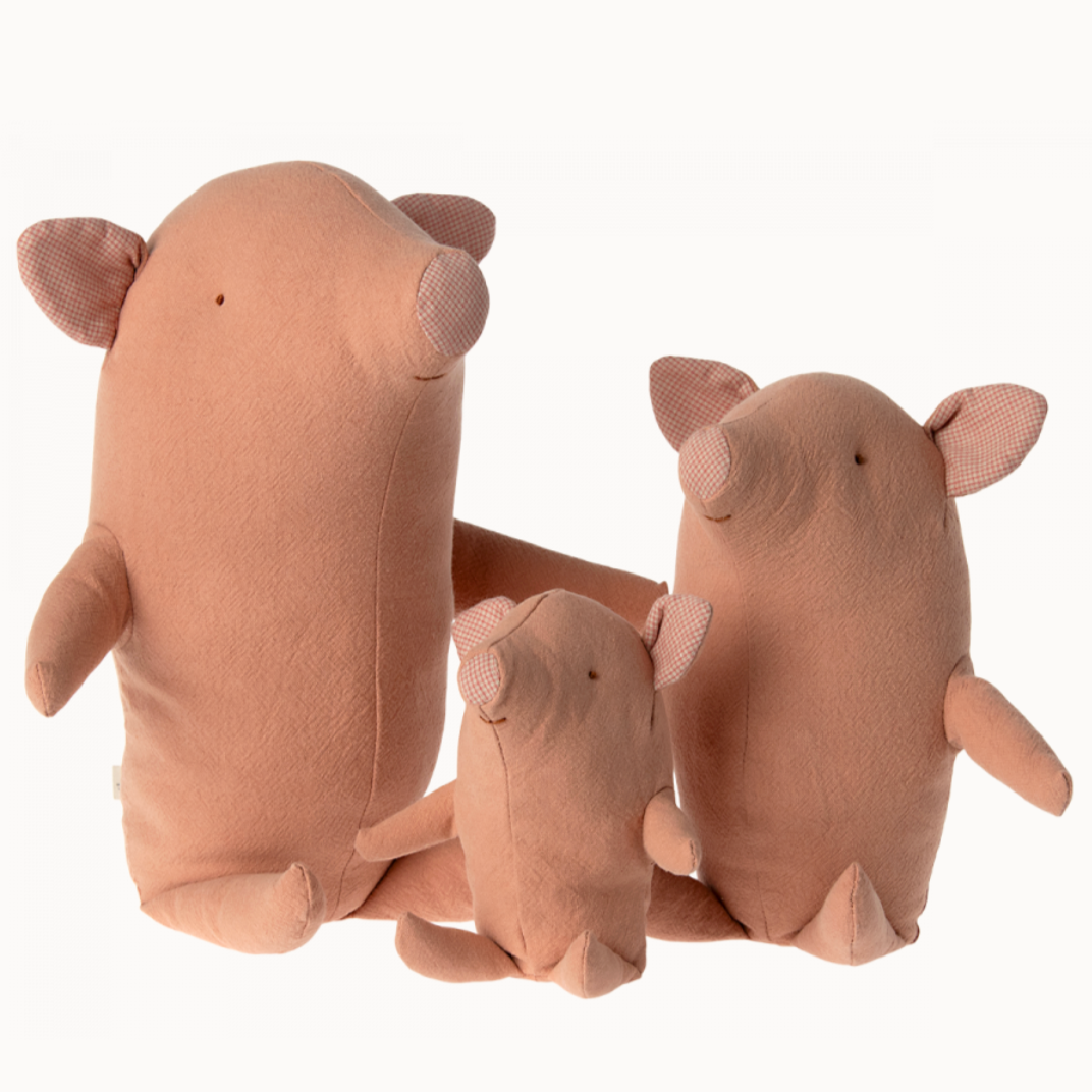 A set of three plush pig toys in different sizes, all with a similar design, in a neutral pink color.