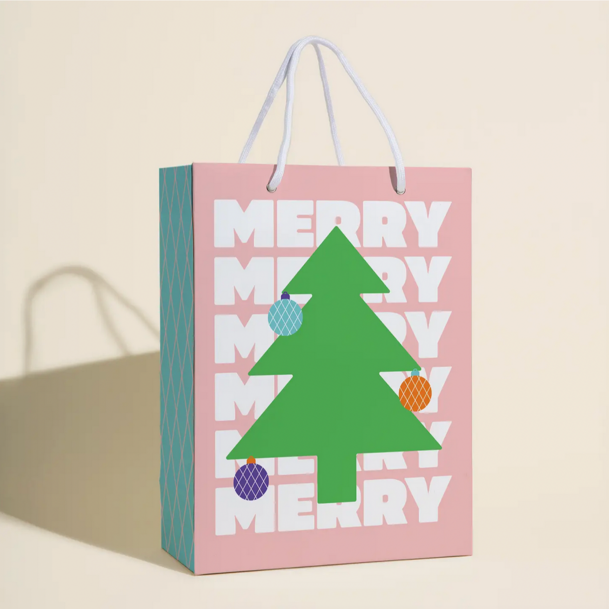 A gift bag with a Christmas tree and ornaments design, featuring text 'Merry Merry' and colored sections on it.