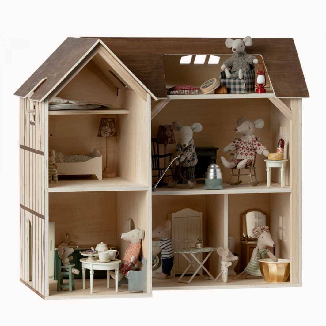 A wooden dollhouse with multiple levels and rooms, furnished with various miniature furniture pieces and toy animal figures.