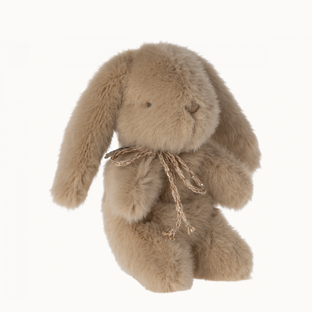 A small plush toy rabbit with a beige and cream color, soft texture, sitting upright with a bow tie.