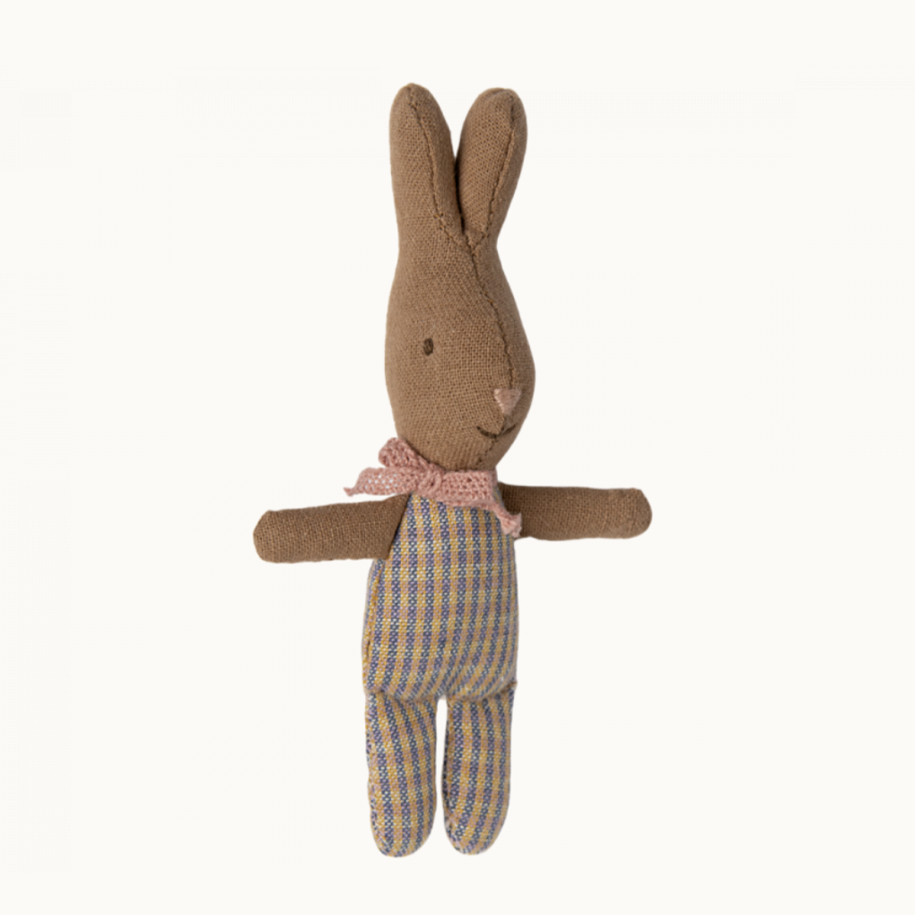 A small plush toy resembling a rabbit with a rose and blue check patterned outfit.