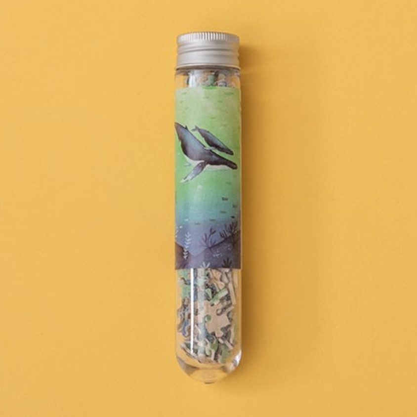 A packaged micro puzzle depicting whales, placed vertically on a yellow background.