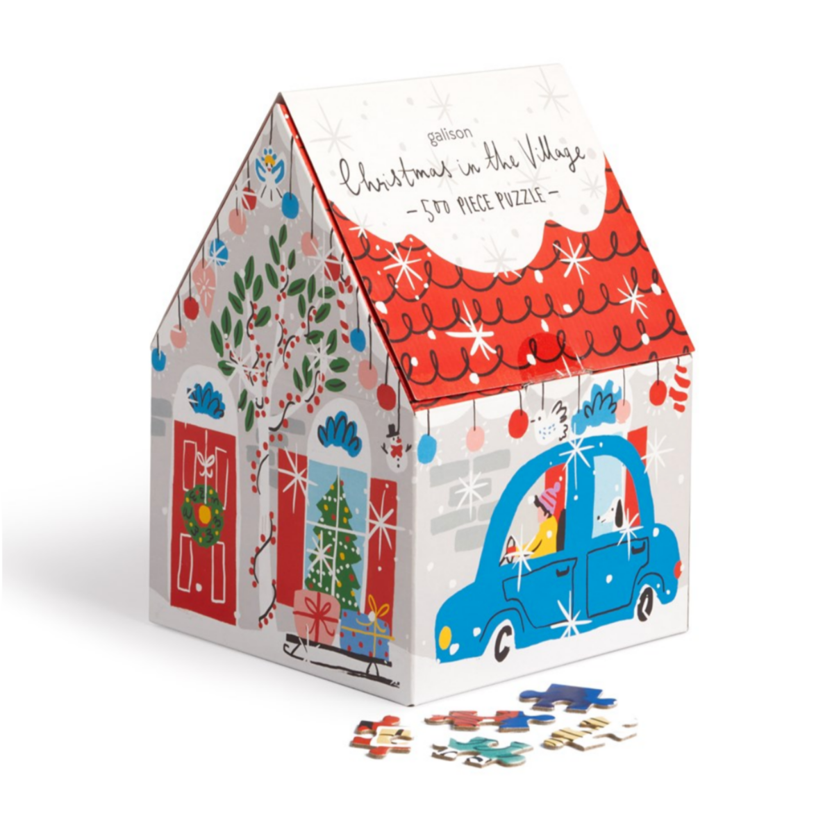 A 500-piece Christmas-themed jigsaw puzzle depicting a decorated house with a red roof, green tree, and festive decorations. The puzzle is packaged in a house-shaped box and displayed with its box and a selection of puzzle pieces.