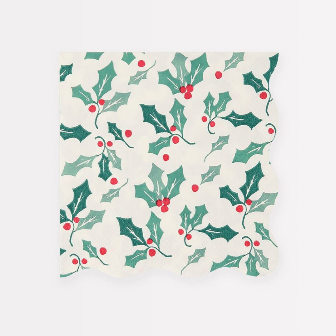 A small square napkin with a holly pattern featuring green leaves and red berries, with a wavy border.