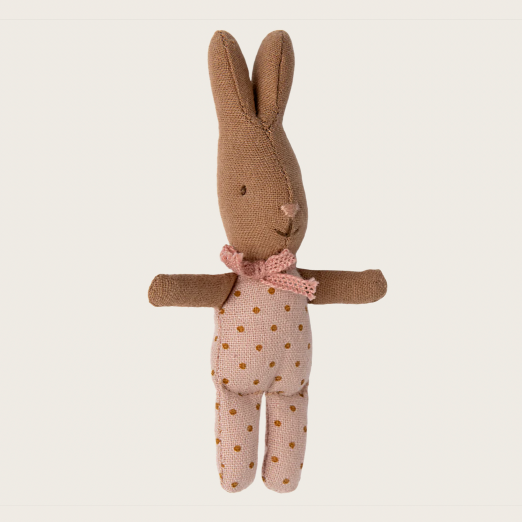 A small plush toy resembling a rabbit with brown fur, a pink bow on its neck, and a polka dot pattern on its body and legs.