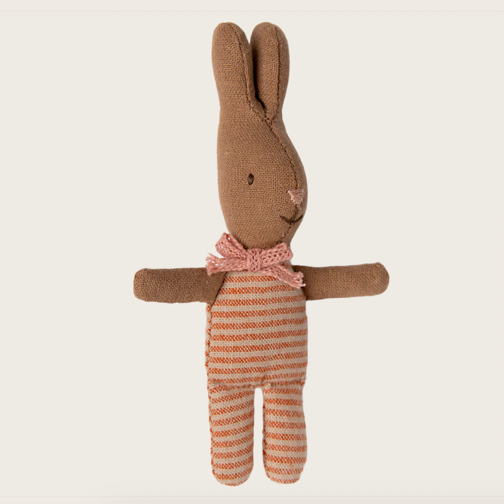 A small plush toy resembling a rabbit with brown fur and a striped orange and brown outfit with a pink bow tie.