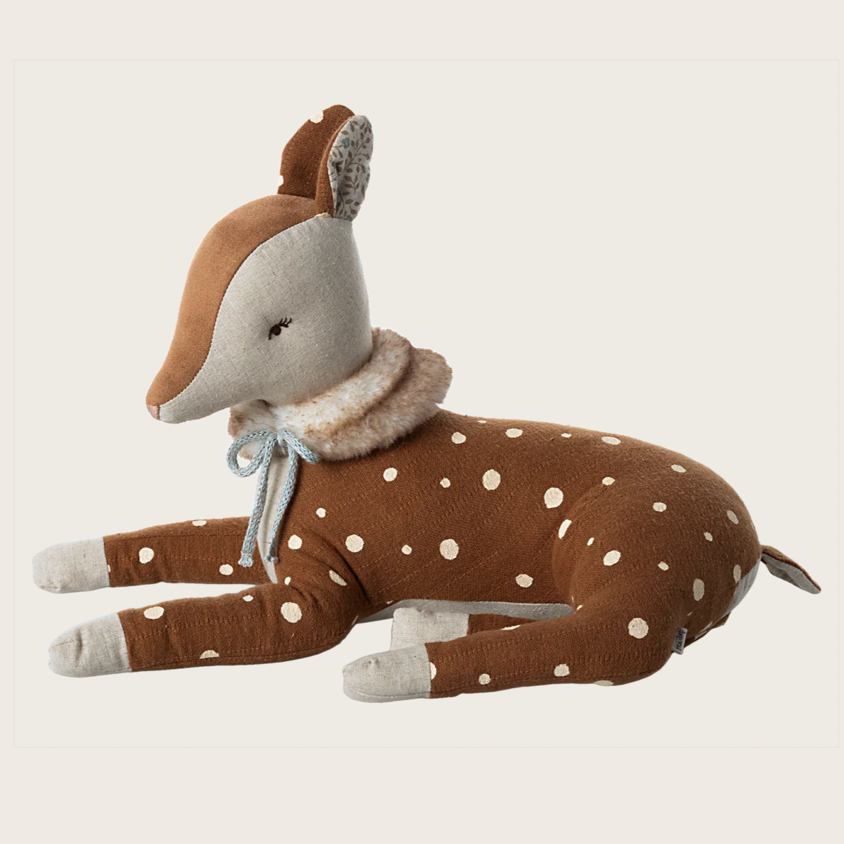 A plush toy resembling a fawn with brown and white coloring and a rose scarf around its neck, lying down.