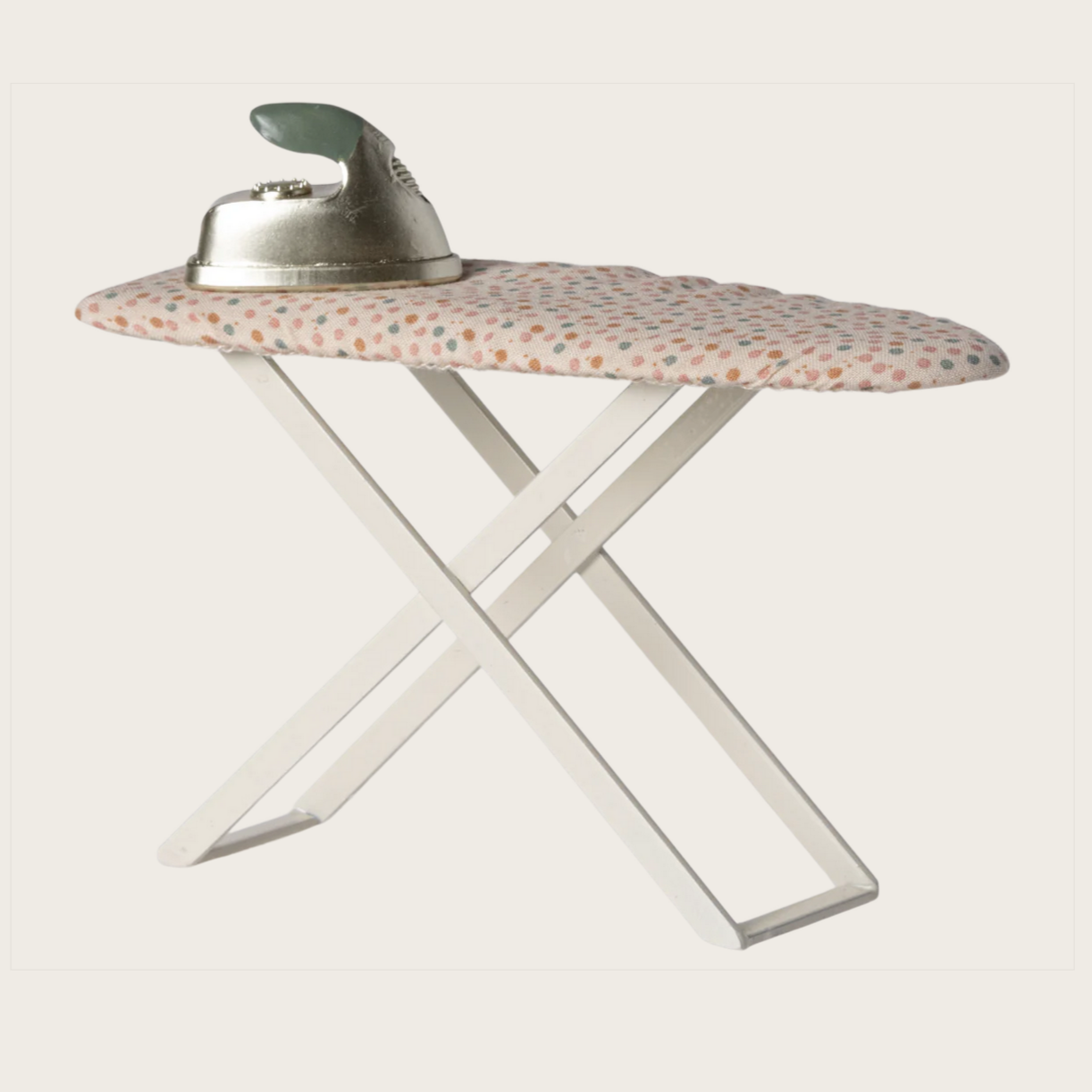 A toy iron and ironing board with a fabric-covered ironing surface featuring a multicolored pattern. The iron is on top of the board, and the board is supported by a white metal frame.
