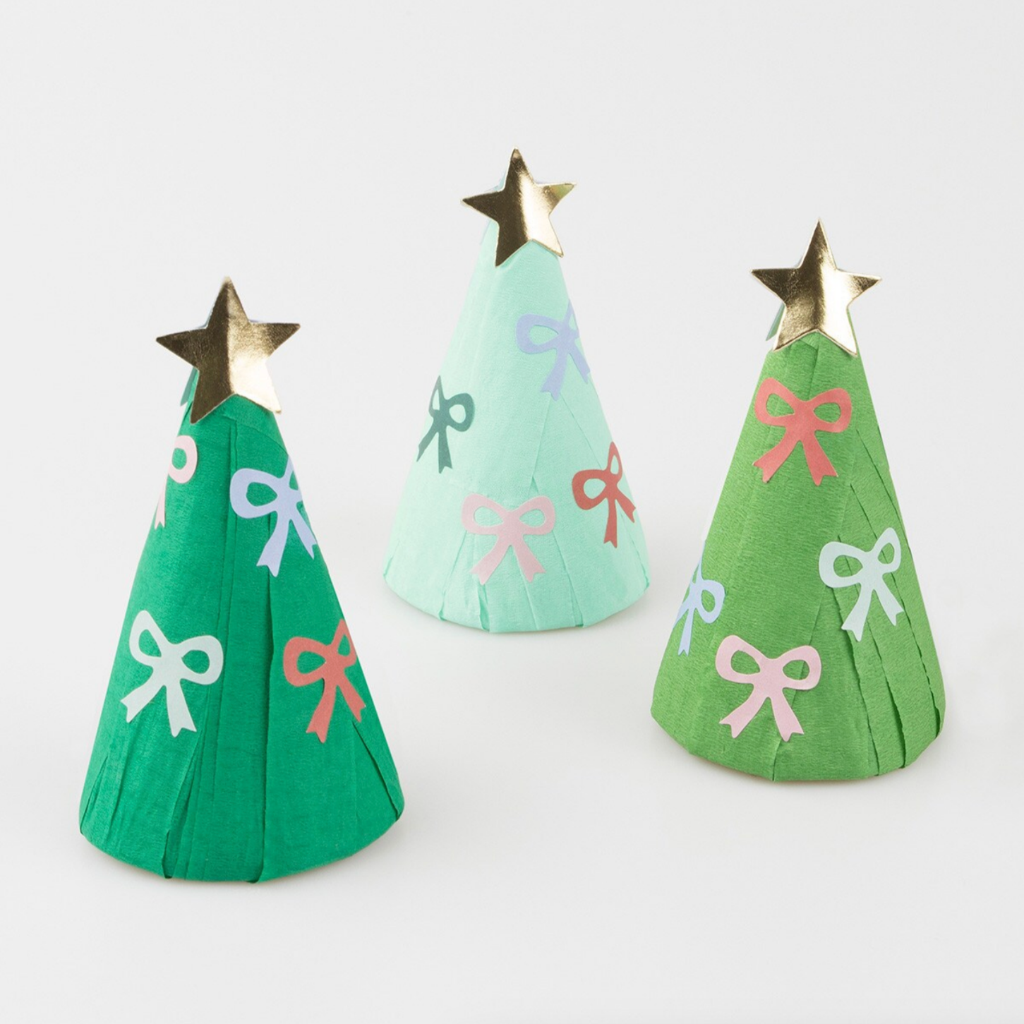 Three Christmas trees made of crepe paper with decorative bows in green, mint, and dark green colors, each topped with a gold star.