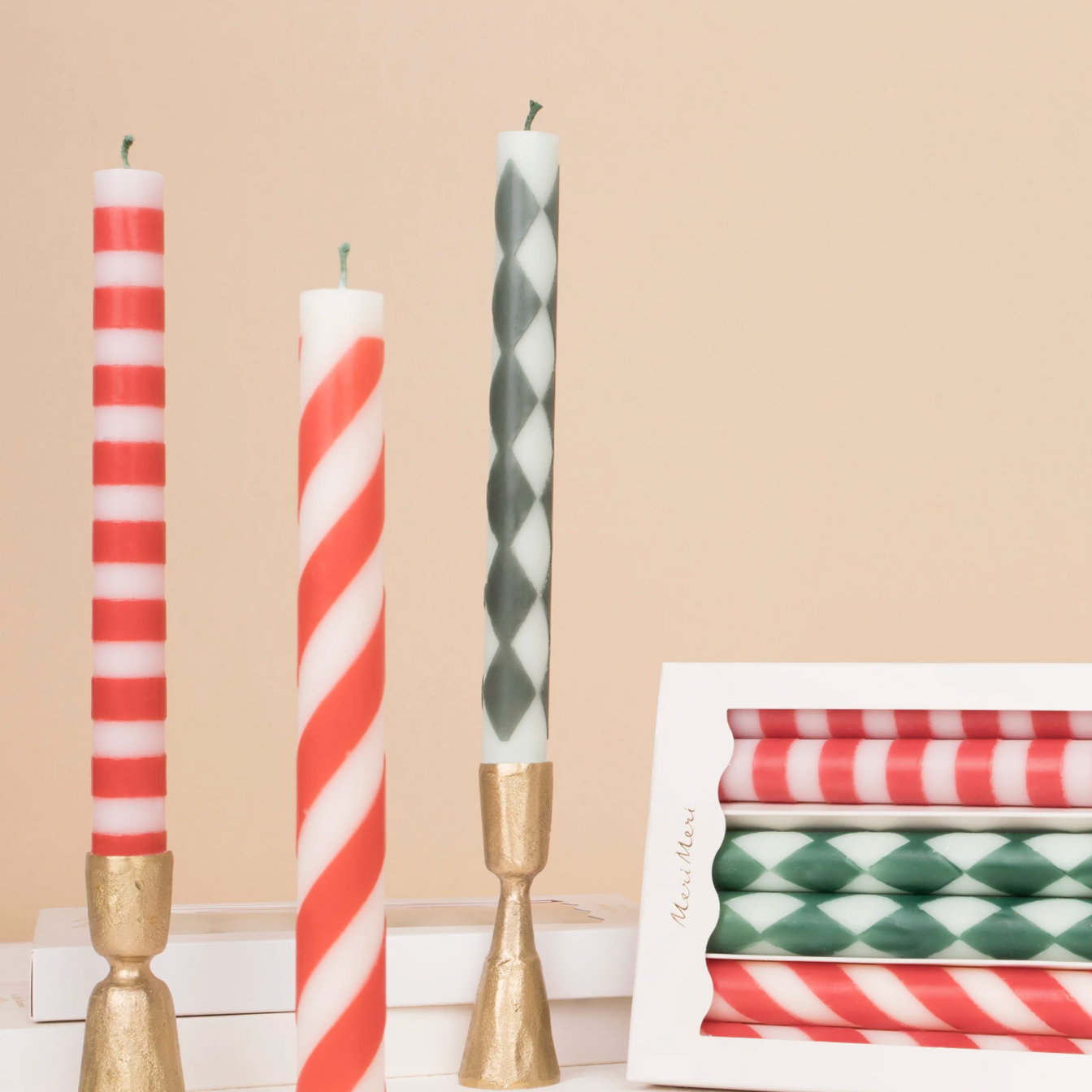 A set of three striped candles with various stripe patterns in red, green, and white colors, displayed on a neutral background.