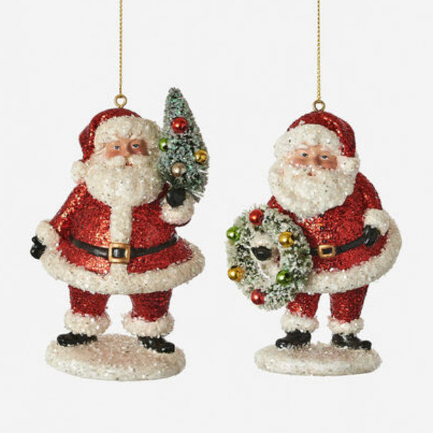 Two resin ornaments depicting Santa Claus with a wreath and a Christmas tree ornament, in red glitter finish, hanging from gold ribbons.