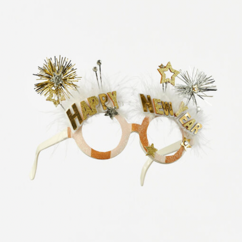A pair of cardboard glasses with 'HAPPY NEW YEAR' written on the top, decorated with glitter, sequins, and artificial flowers.