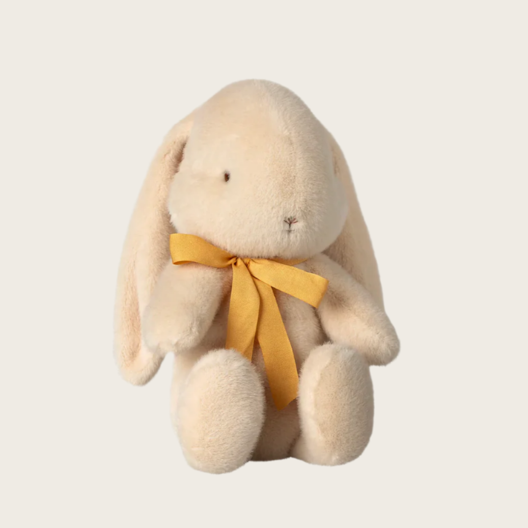 A medium-sized plush toy resembling a cream-colored bunny with a yellow bow around its neck.