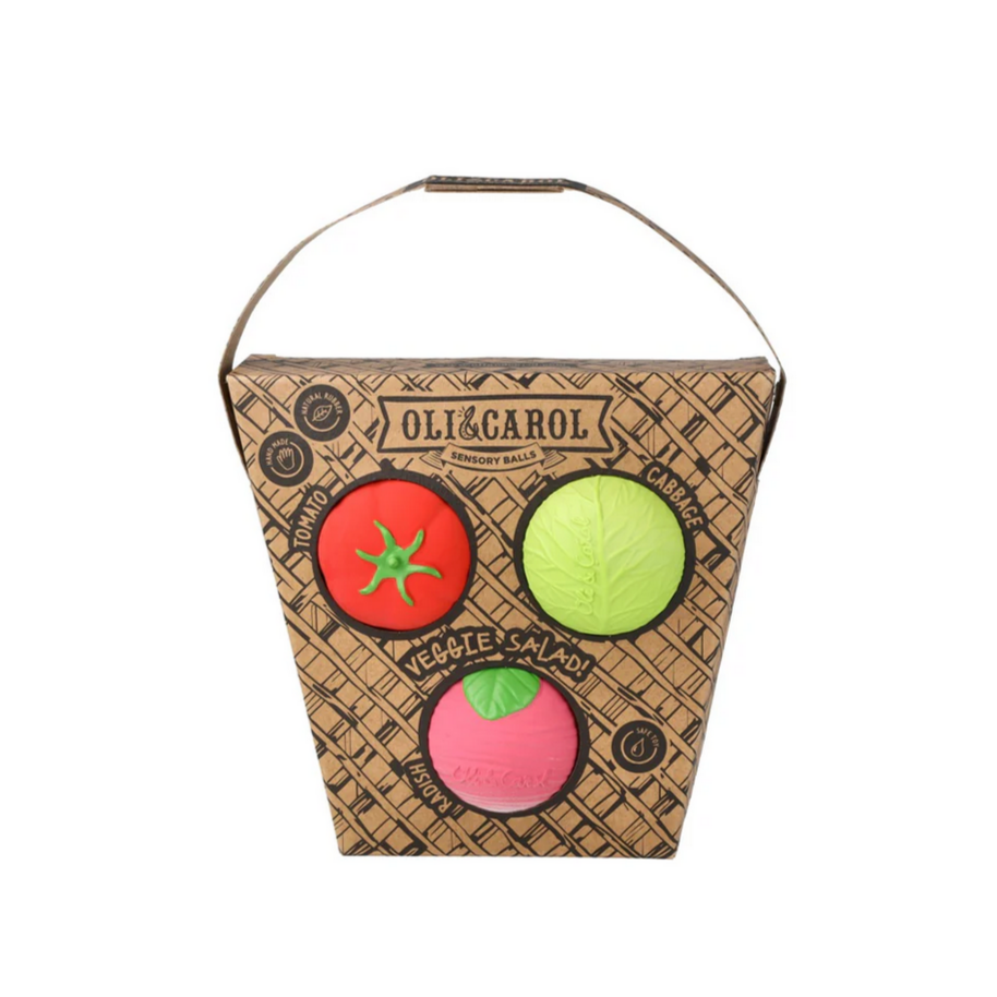 A set of three colorful baby sensory balls in the shapes of a radish, tomato, and cabbage, packaged in a cardboard container with a handle.