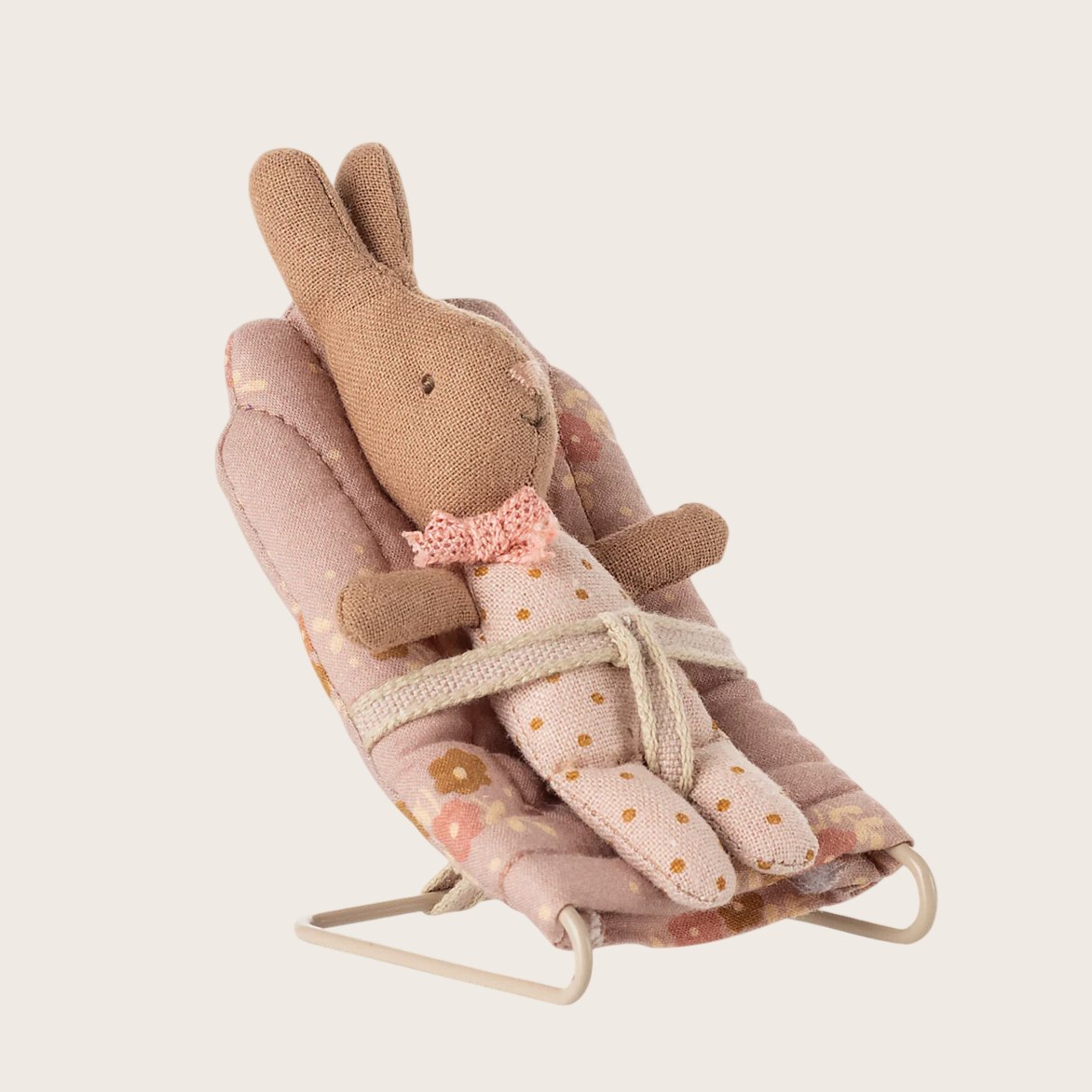 Baby bouncer with a plush rabbit toy on a light beige background