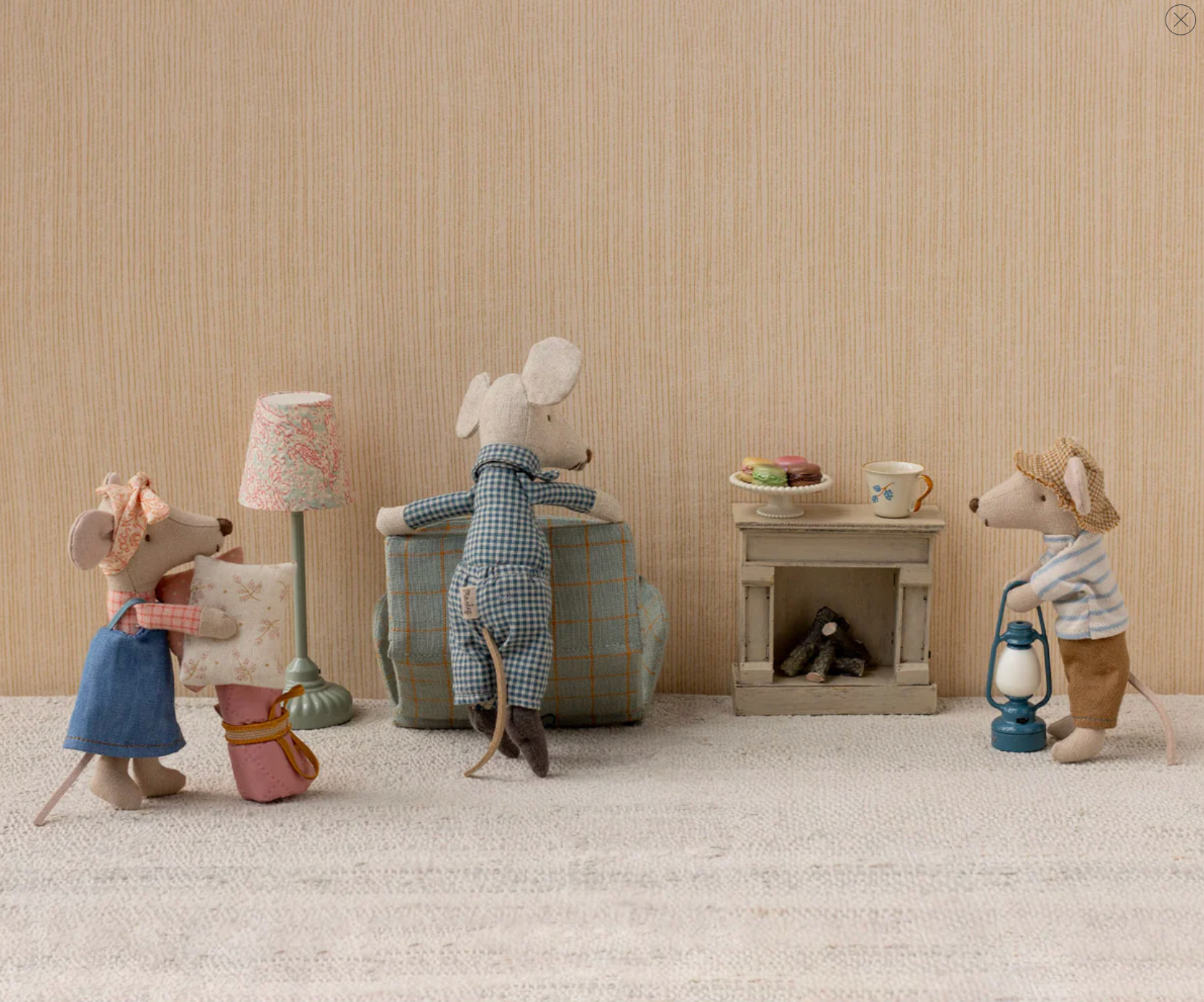 Miniature mouse figures in a cozy room with a fireplace and lamp.