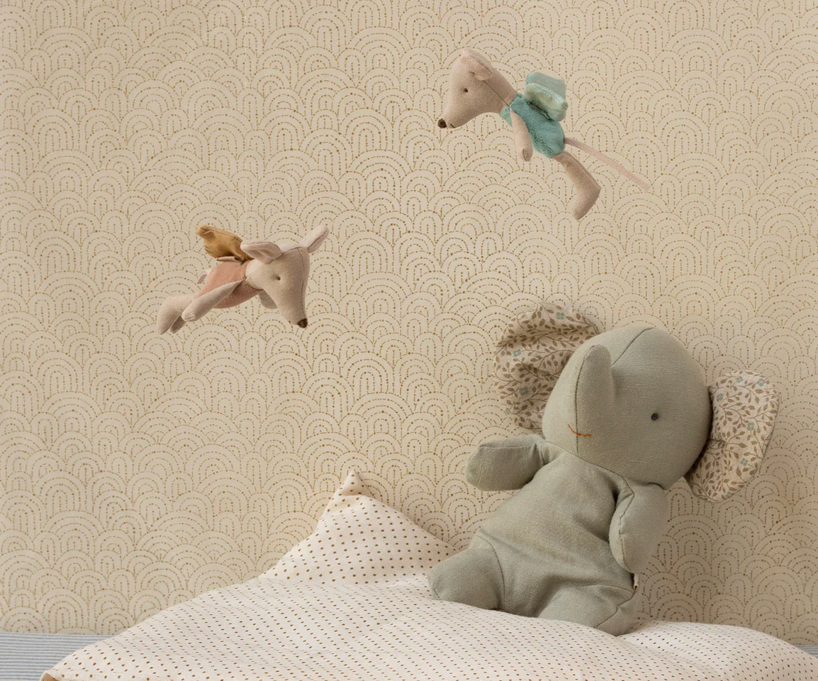 Children's room with stuffed animal toys on a bed against a patterned wall.