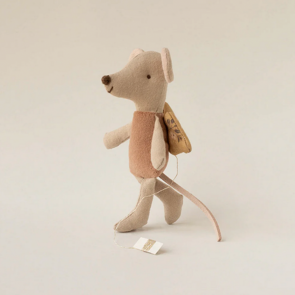 Stuffed mouse toy with a backpack on a beige background