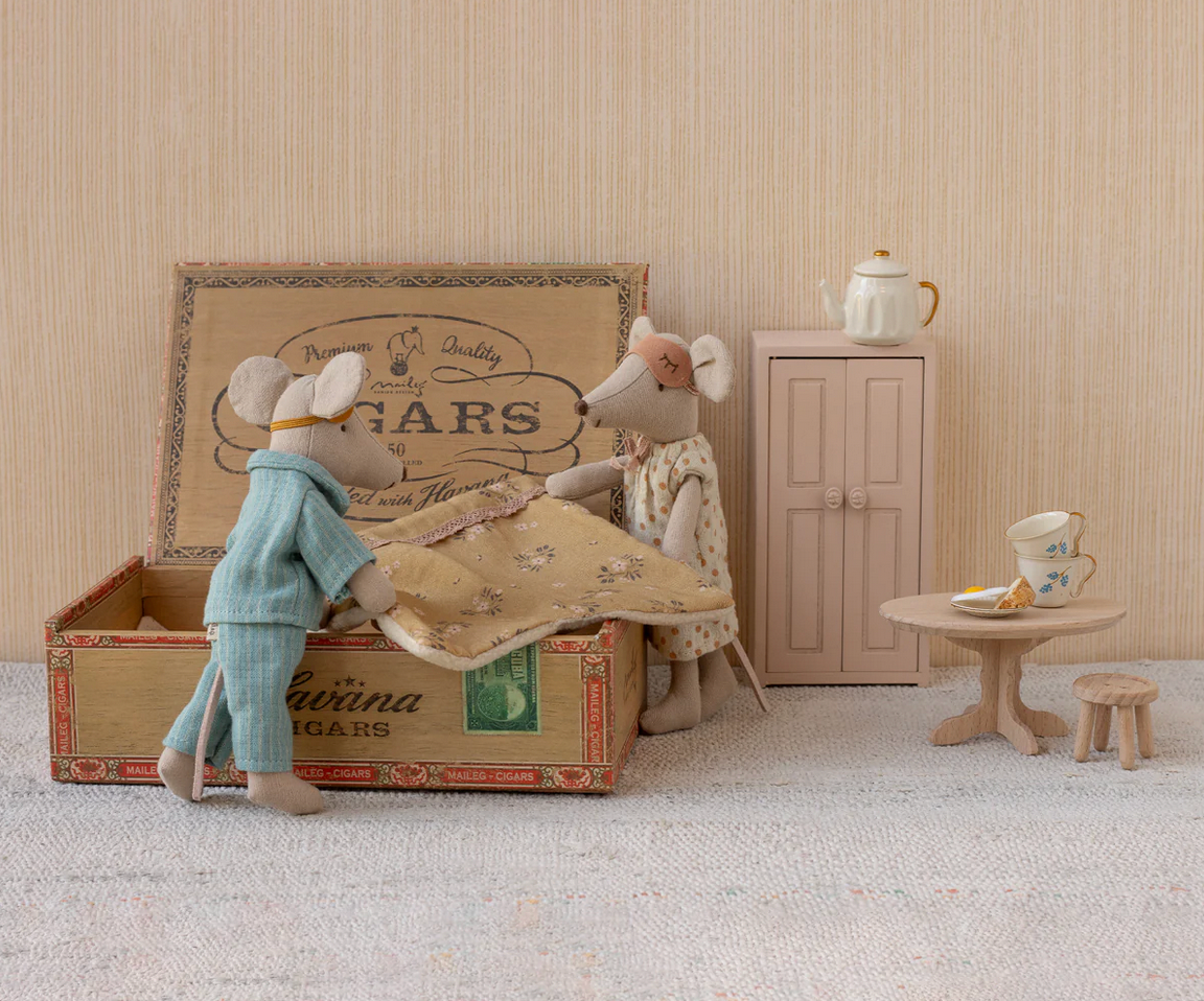 Two toy mice in a room with a vintage suitcase, small table, and cabinet.