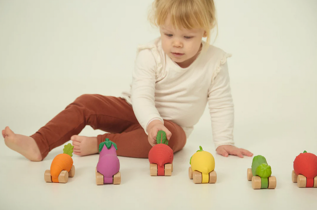Child playing with colorful wooden toy vegetables on a white background