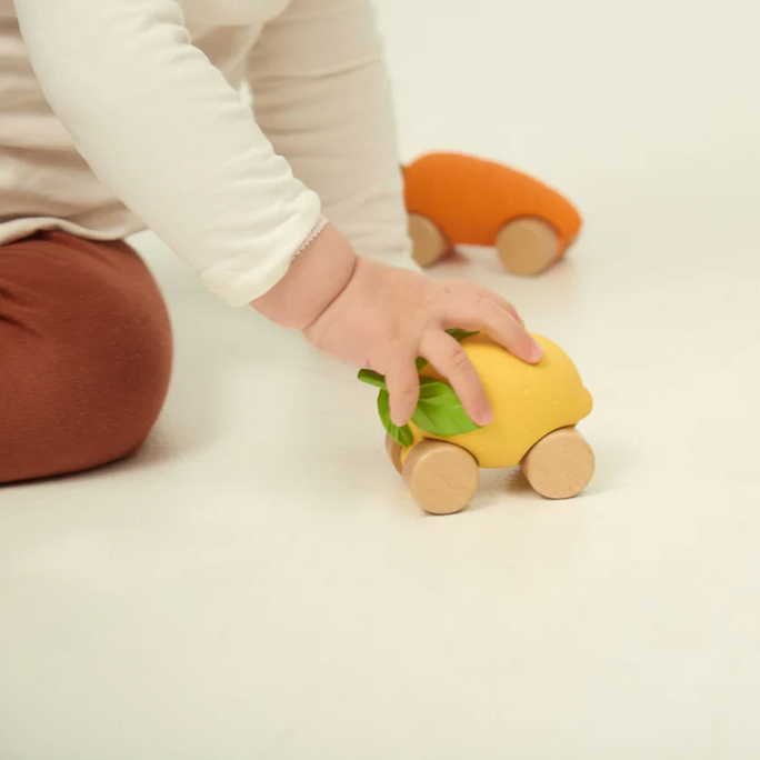 Child playing with a yellow toy car on a light background