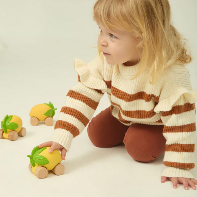 Child playing with toy cars on a plain background