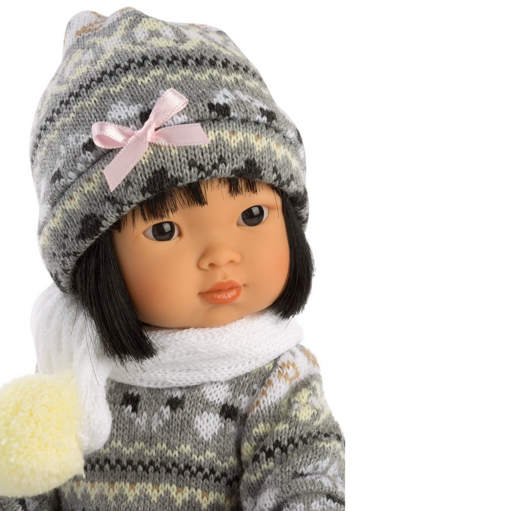Doll wearing a gray knitted hat with a pink bow and matching outfit on a white background.