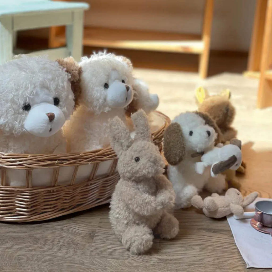 Plush toys including teddy bears and a rabbit on a wooden floor.