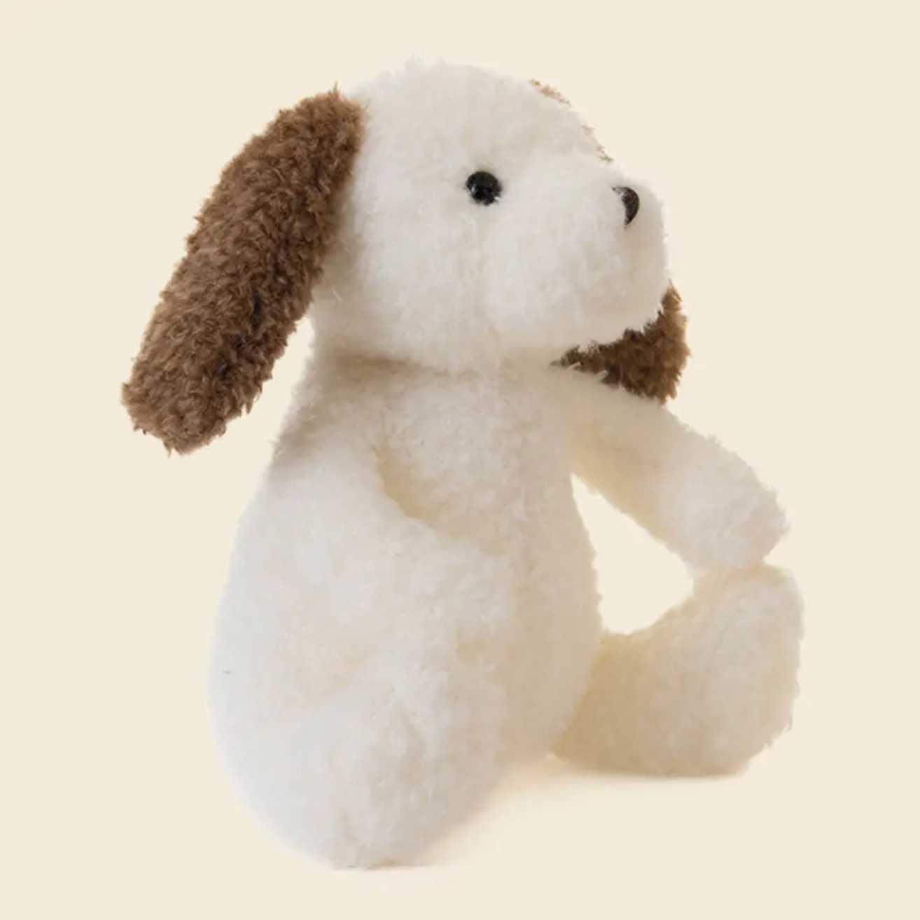 Stuffed dog toy with brown ears on a beige background