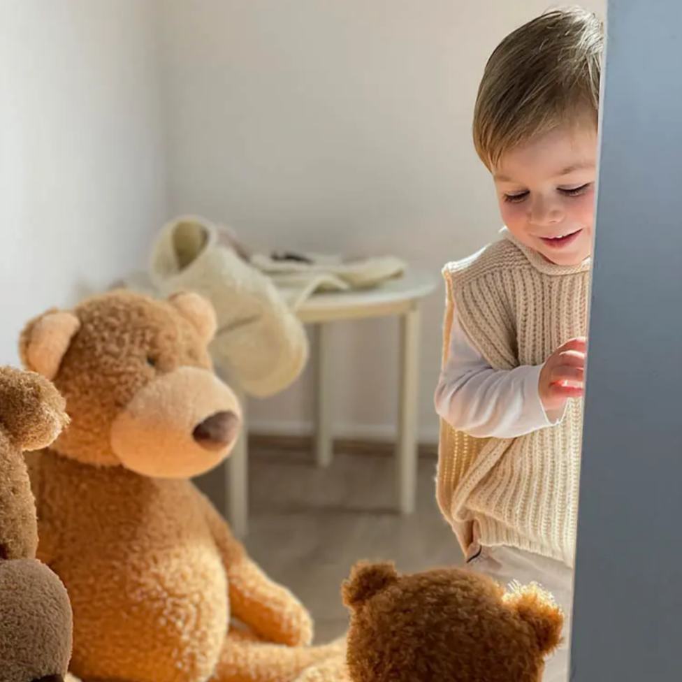 Child interacting with teddy bears in a room
