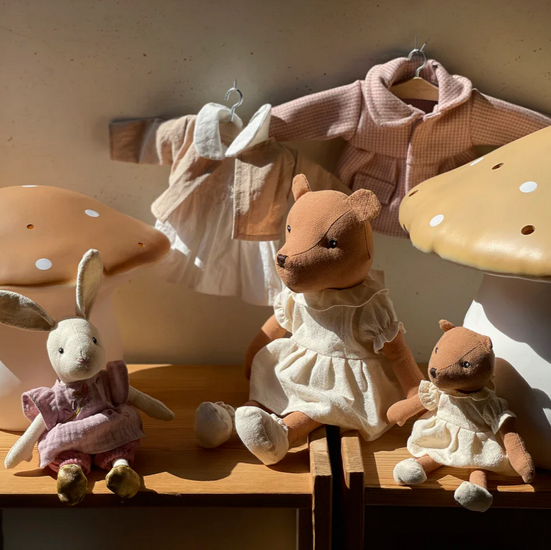 Stuffed animals on a wooden surface with mushroom-shaped lamps in the background
