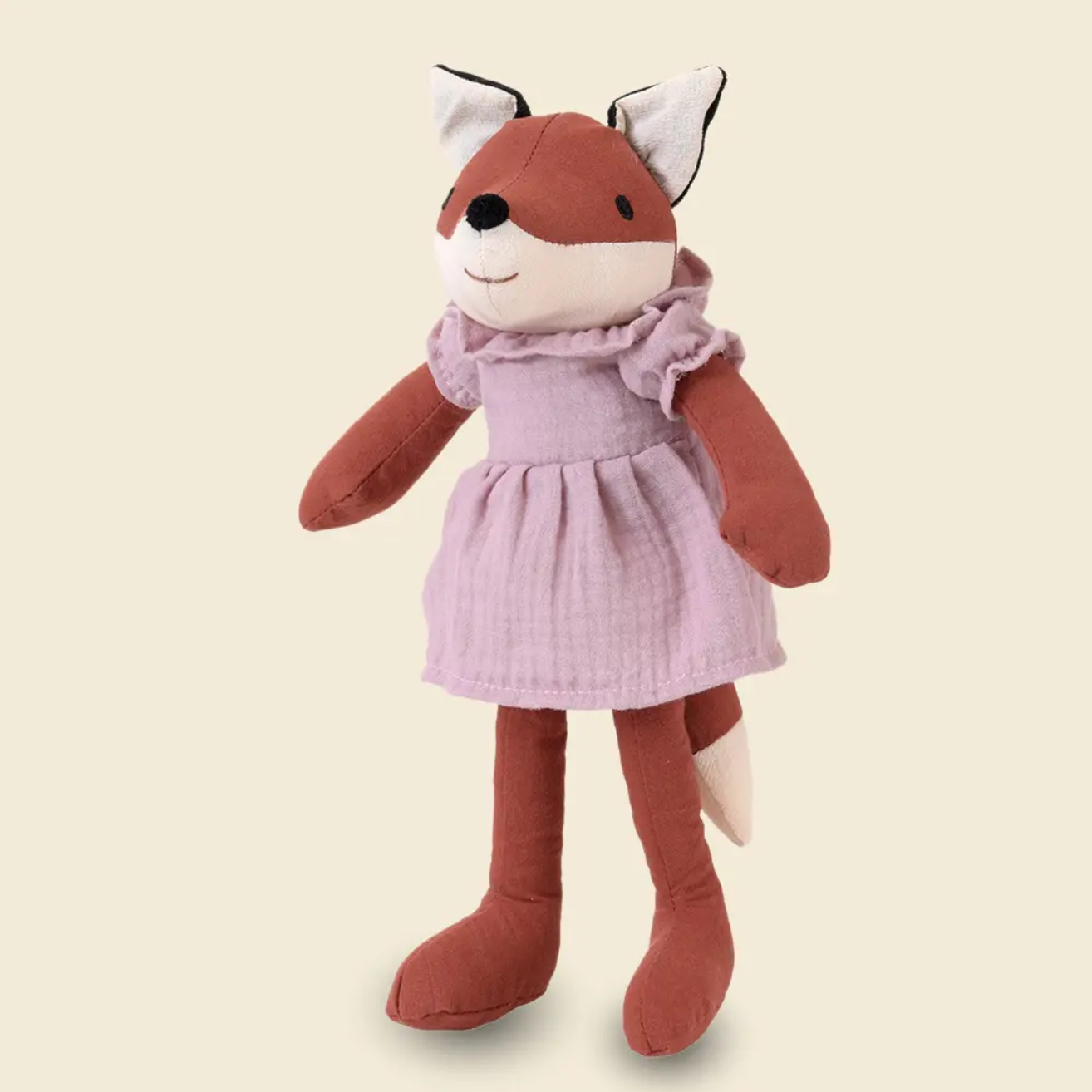 Stuffed fox toy wearing a pink dress on a beige background