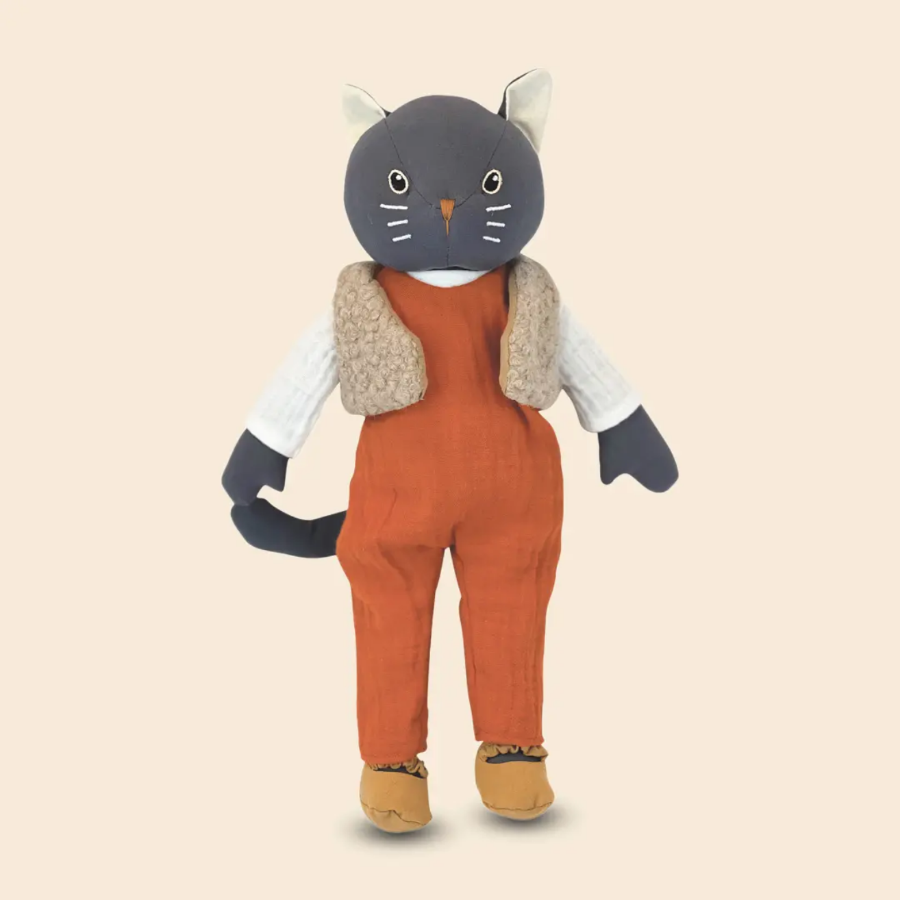 Stuffed toy cat in orange overalls with a beige vest on a beige background