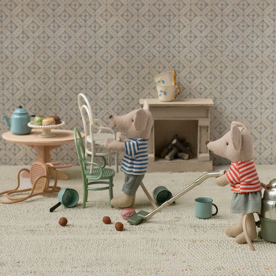 Two toy mice in a miniature room with furniture and toys.