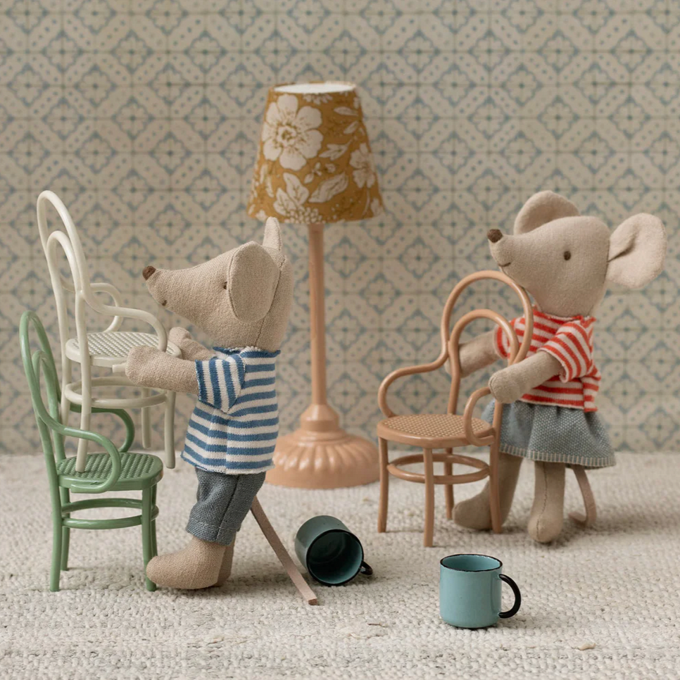 Two toy mice in a miniature room setting with furniture and decor.