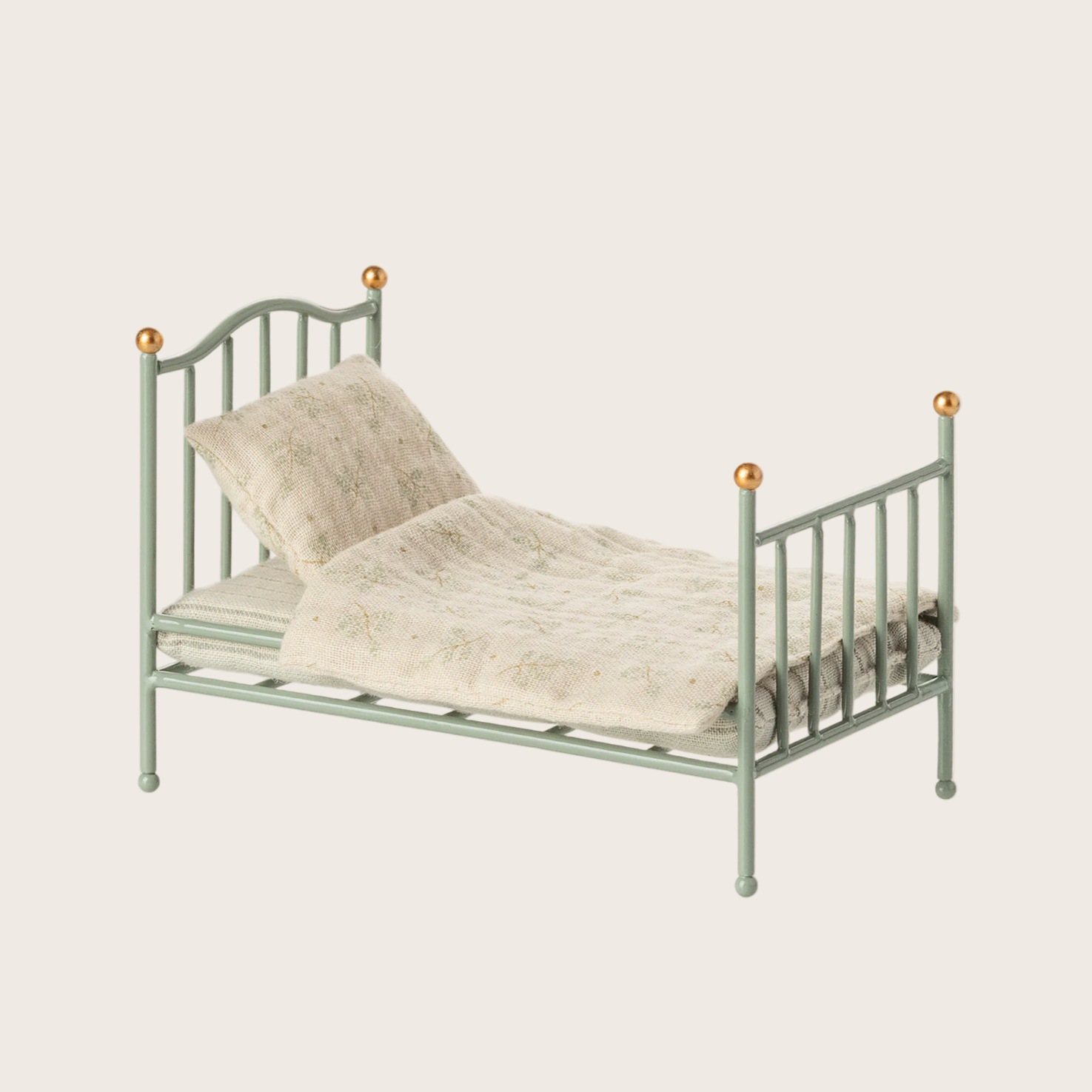 Green metal bed with beige bedding on a light gray background