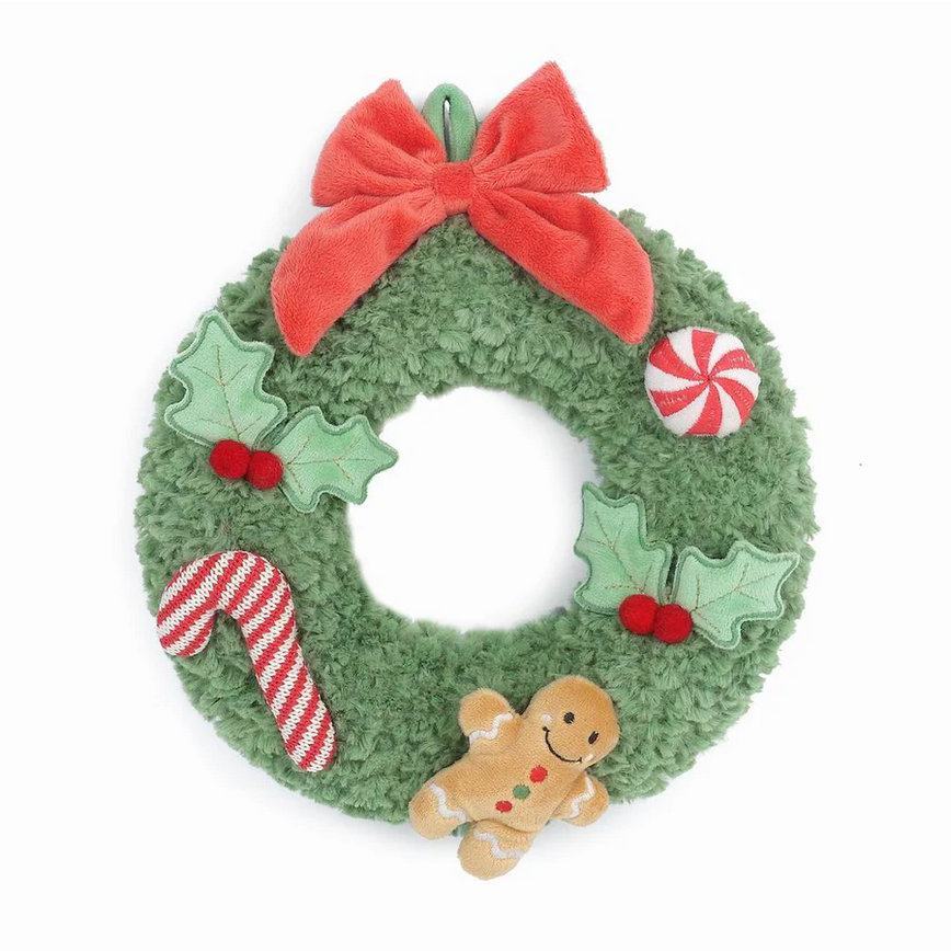 Green plush Christmas wreath with gingerbread man, candy cane, and holly decorations on a white background.