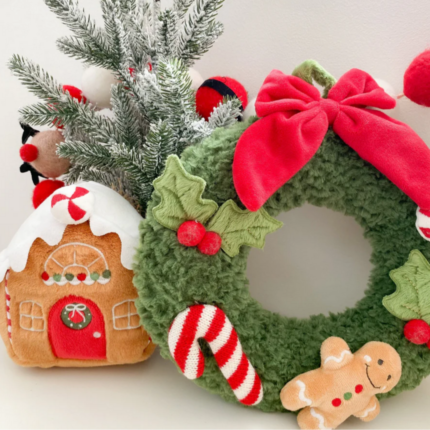 Christmas wreath with gingerbread man, candy cane, and gingerbread house decorations on a white background.