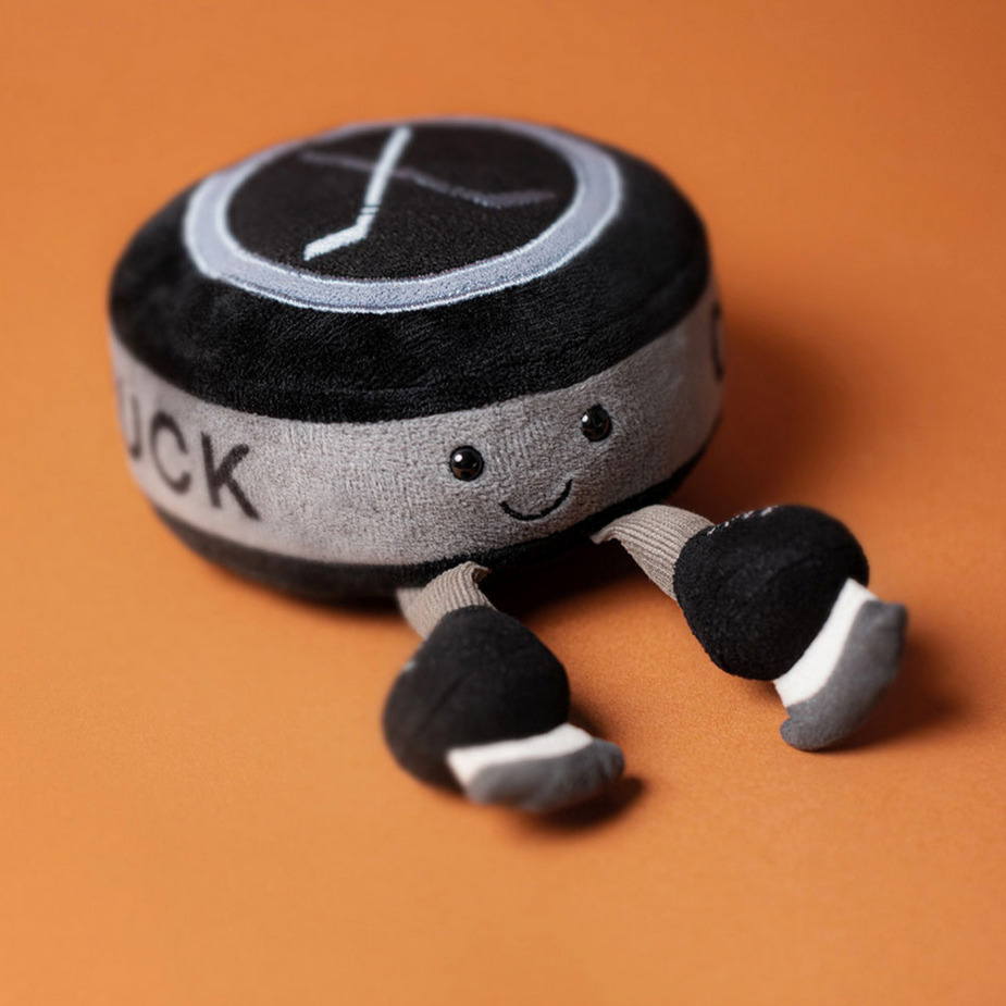 Plush toy hockey puck with legs on a brown background