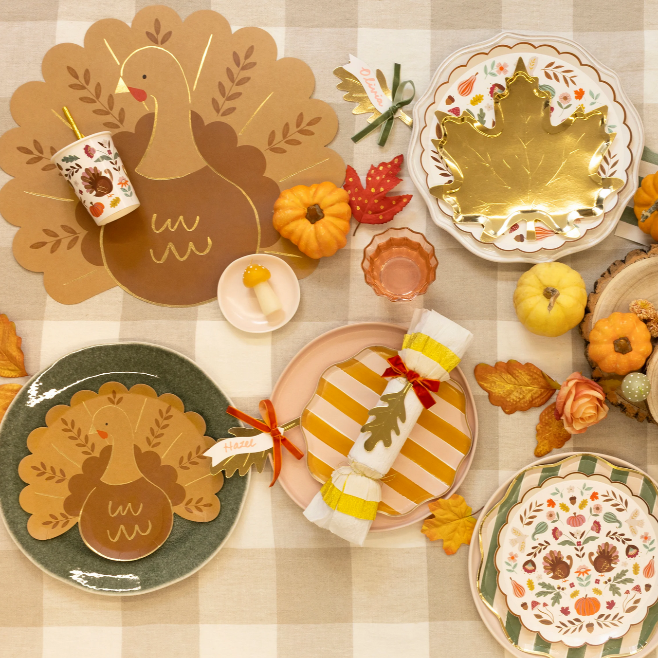 Thanksgiving-themed table setting with decorative plates, pumpkins, and a checkered tablecloth.
