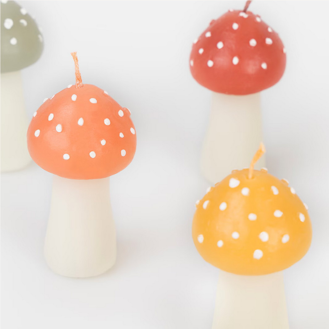 Three mushroom-shaped candles with polka dot caps on a white background