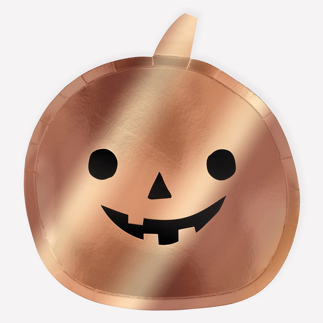 Bronze-colored pumpkin-shaped plate with a face on a white background