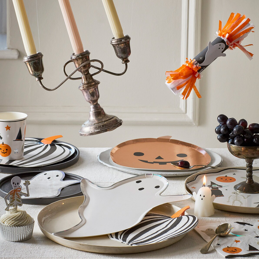 Halloween-themed table setting with ghost plates, candles, and decorative items.