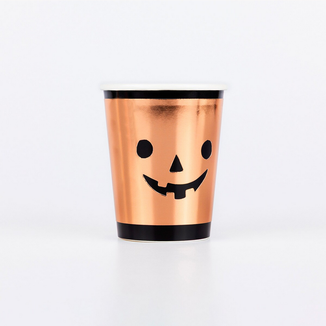 Copper-colored cup with a black lid and jack-o'-lantern face design on a white background