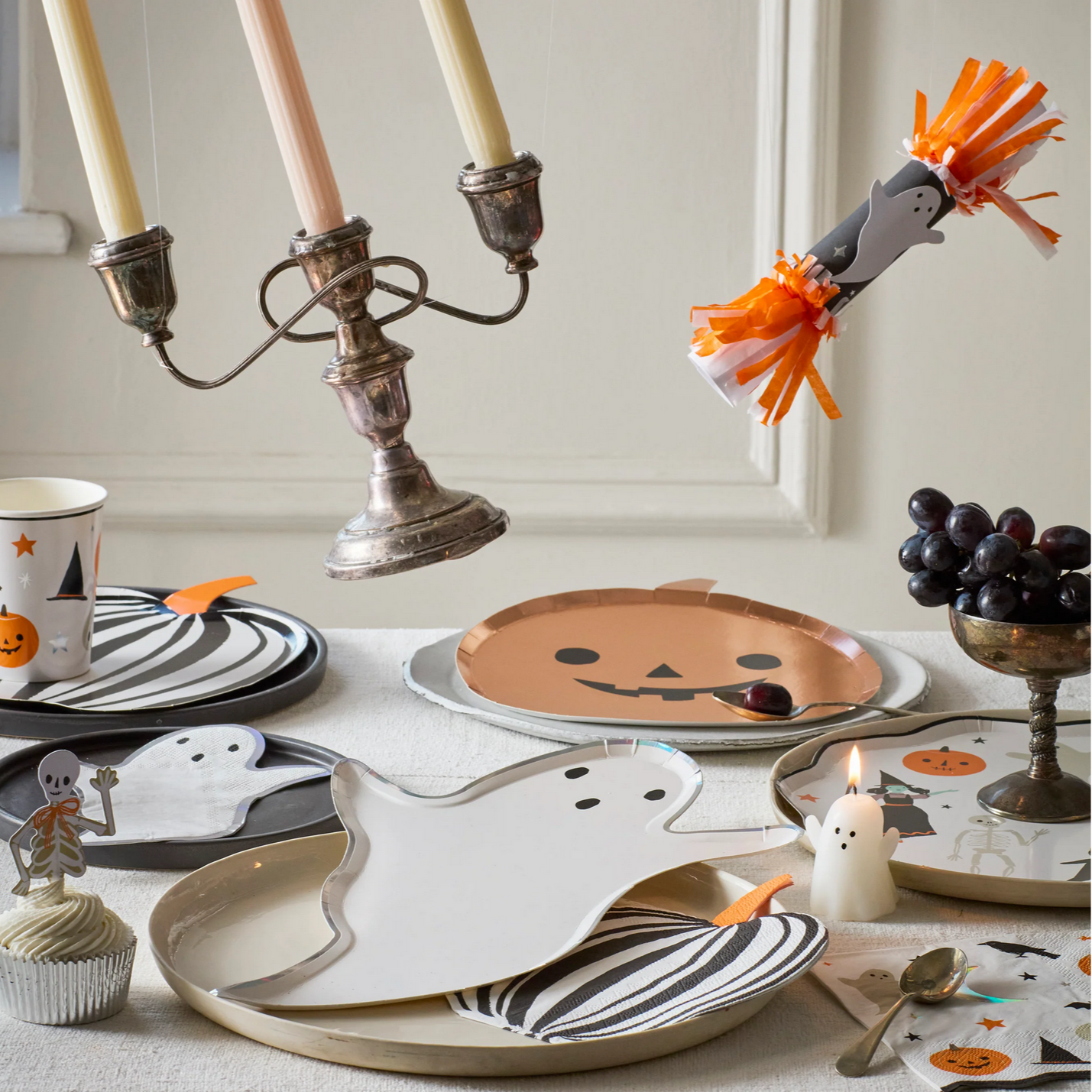 Halloween-themed table setting with ghost plates, candles, and decorative items.