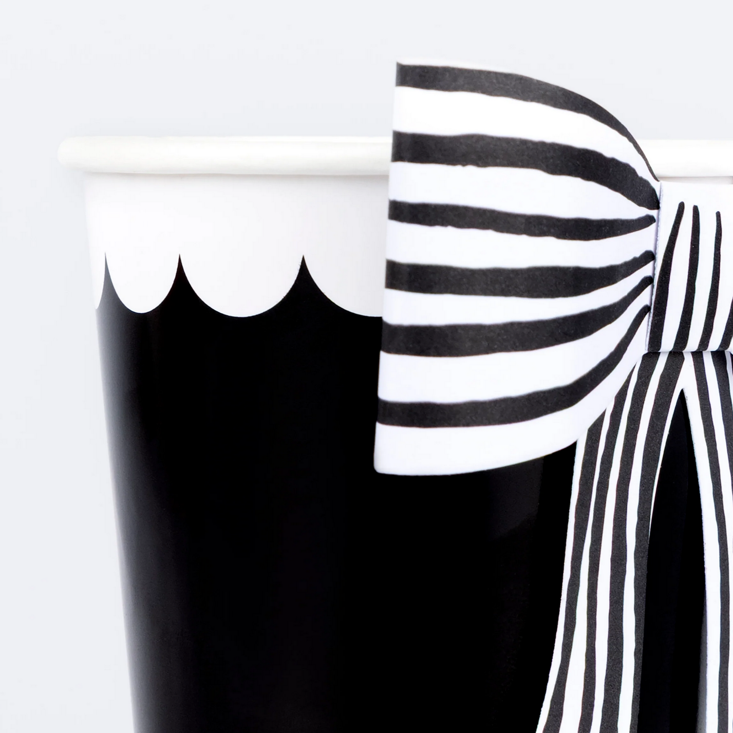 Black and white striped cup with a bow detail on a white background