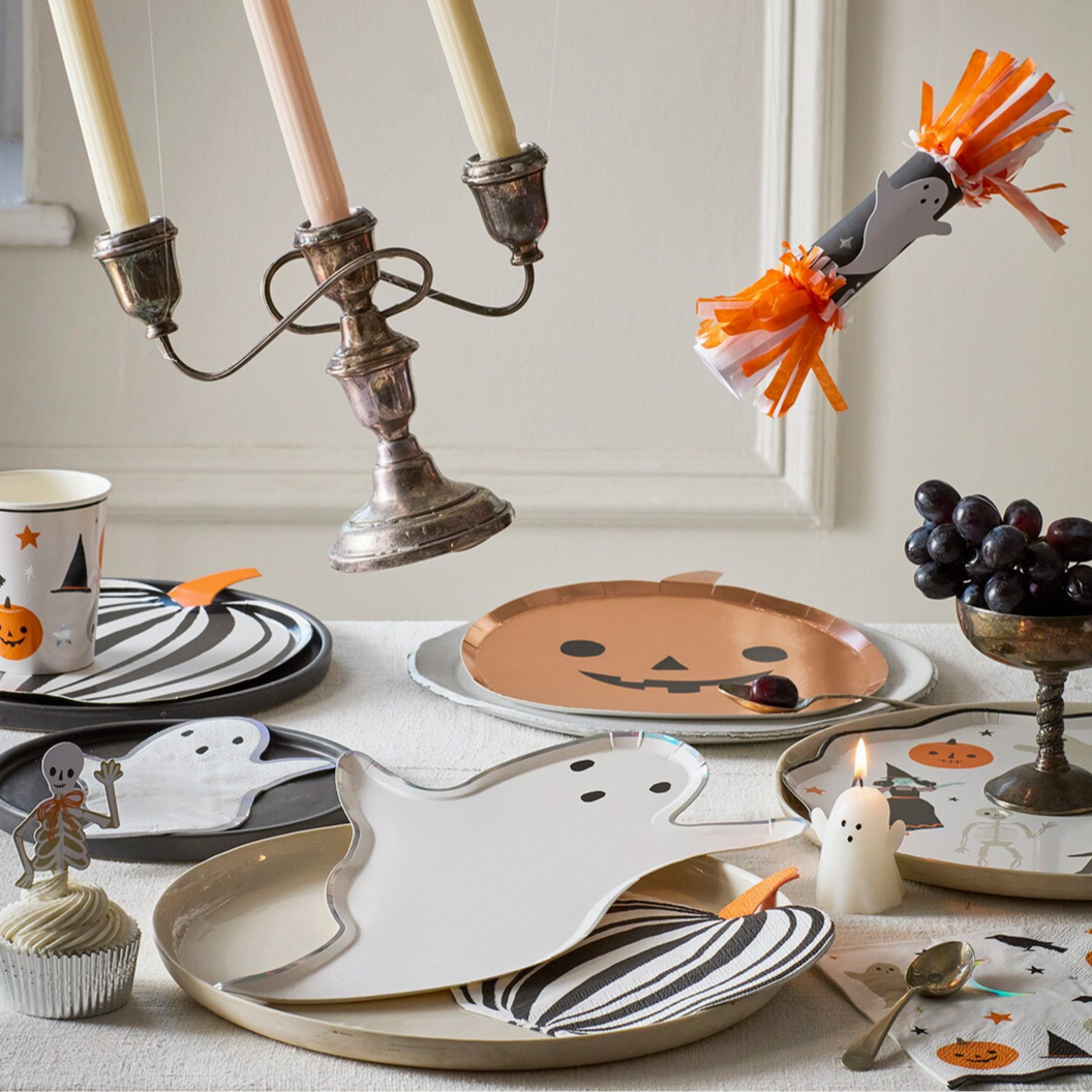 Halloween-themed table setting with ghost plates, candles, and decorative items.