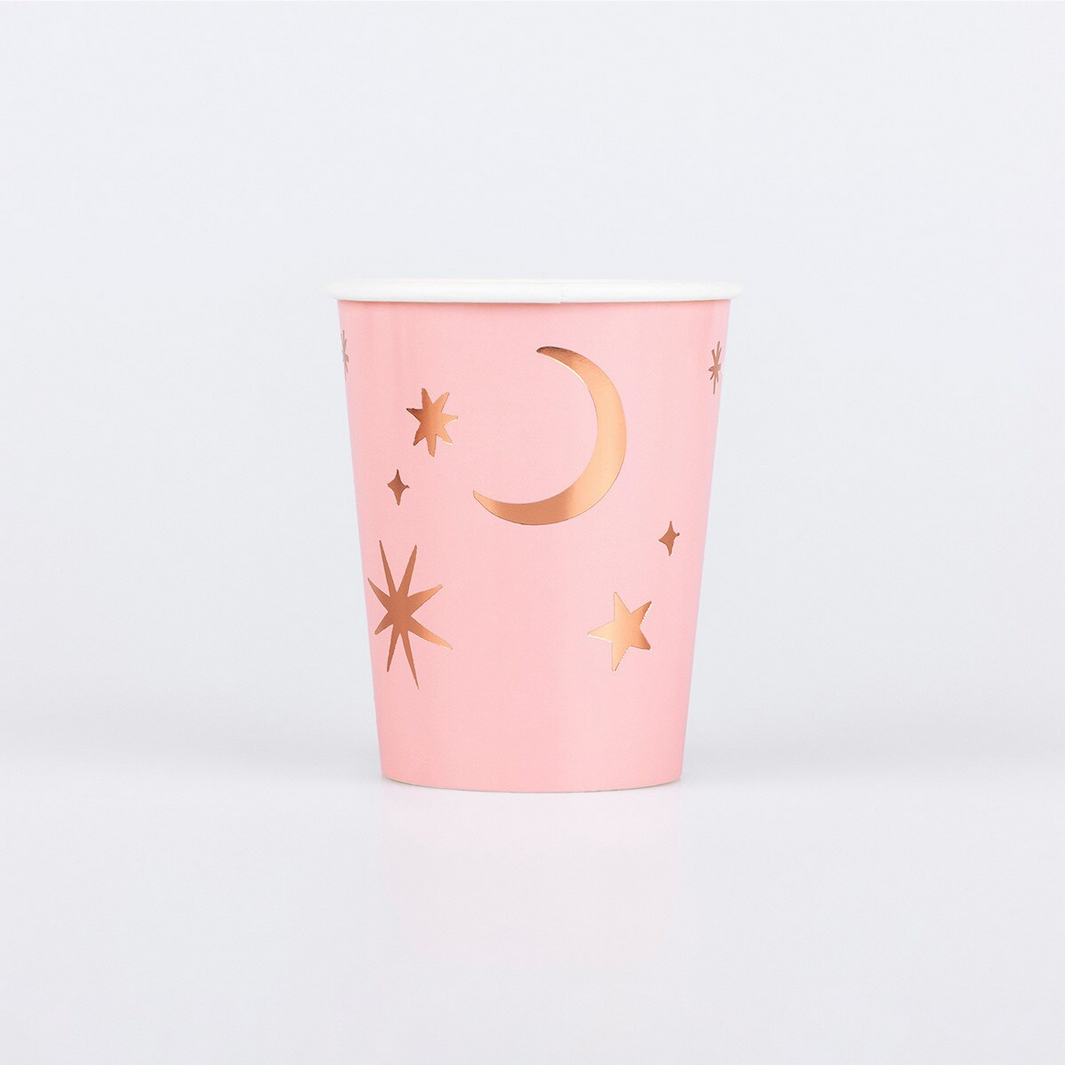 Pink cup with gold star and moon designs on a white background