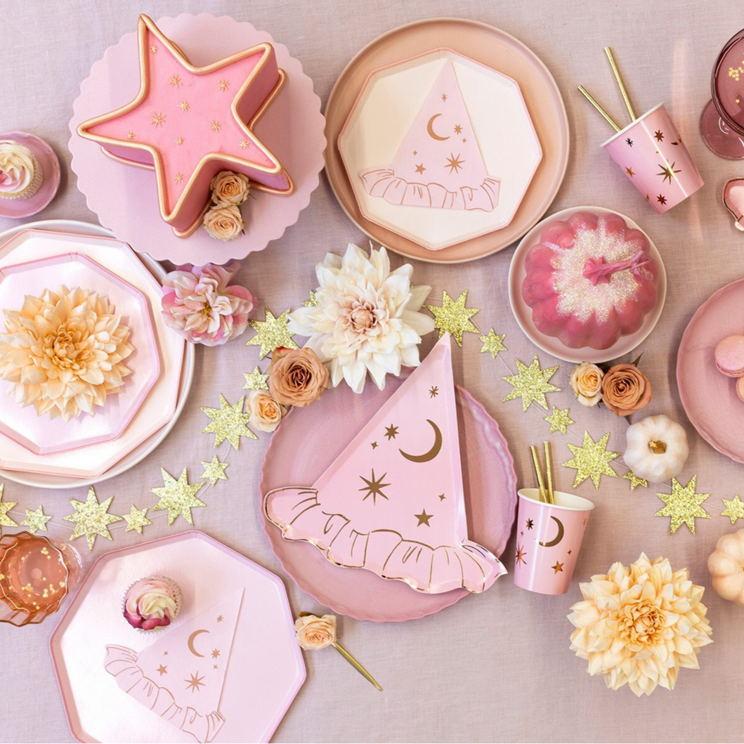 Pink party hats, plates, and decorations with flowers on a light background